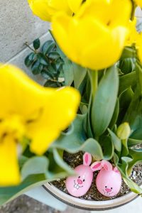 easter eggs hiding in a pot of yellow flowers