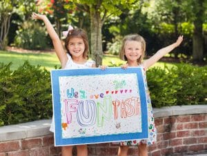 two girls holding a we love fun pasta decorated sign