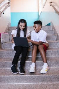 young boy and girl studying on stairs together and looking at a laptop