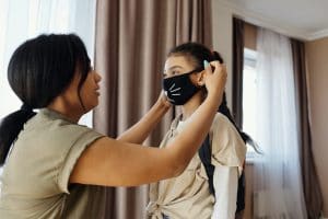 mother putting a face mask on her daughter